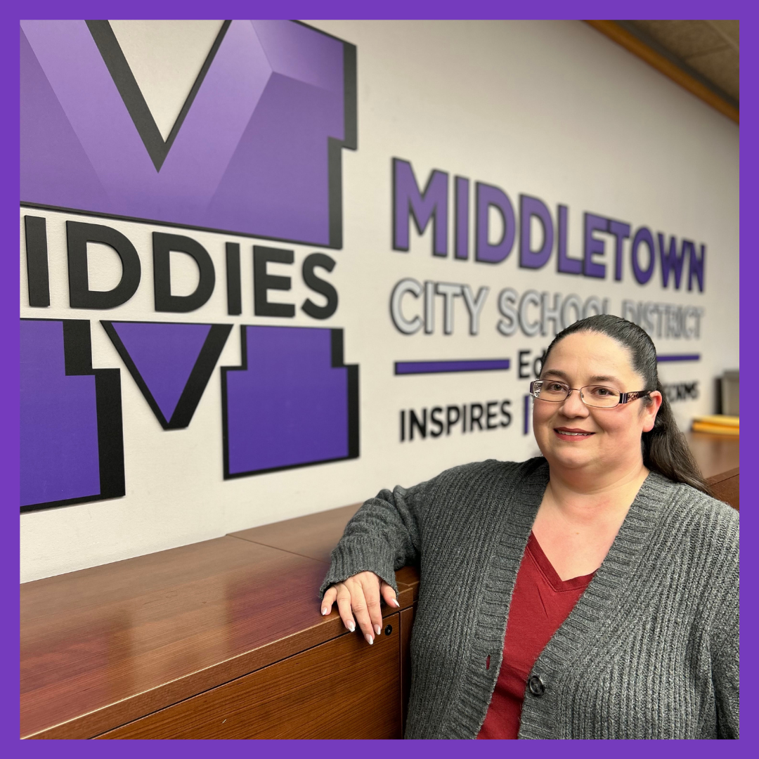 Woman poses for photo in front of Middletown City School District sign